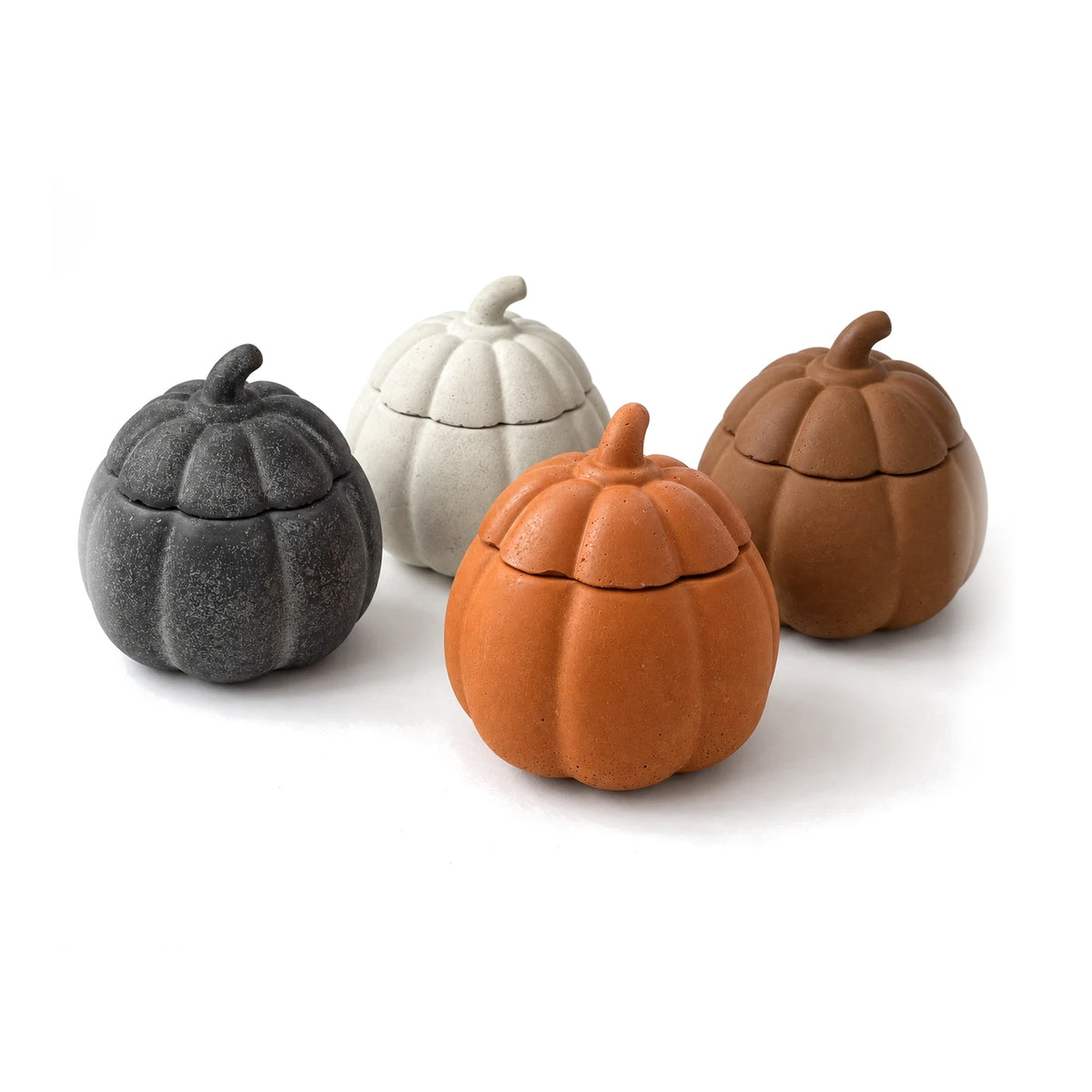 Four concrete pumpkin candles with lids: graphite, white, orange and brown