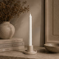 White straight pillar candle in a stone holder at home