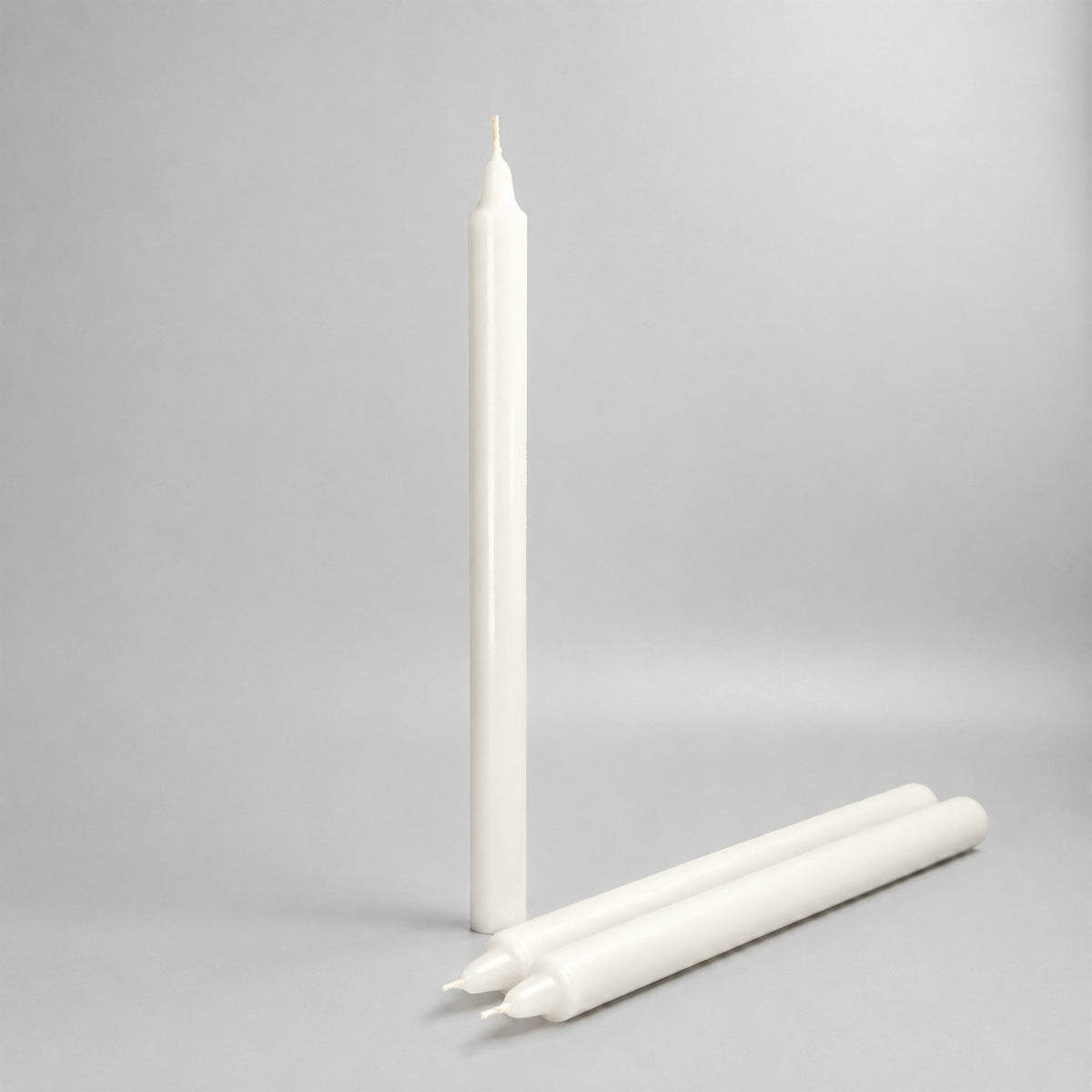 One standing and two lying white pillar candles